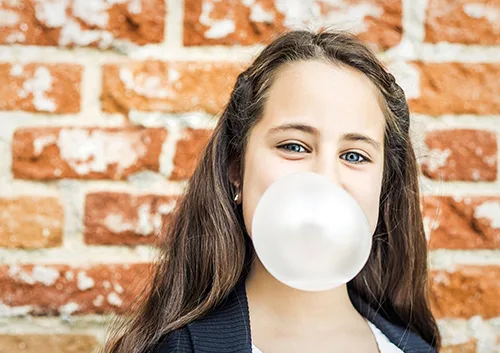 Little Happy Girl Blowing a Chewing Gum