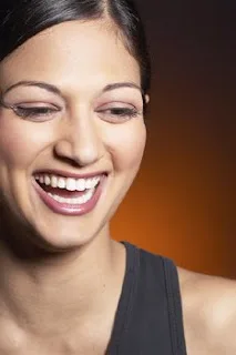 Smiling woman with healthy teeth against warm brown background in professional portrait setting.
