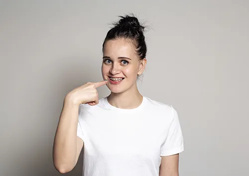 Joyful young woman showing braces on her teeth. Isolated on whit