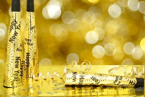 Gold luxury cosmetic bottles with bokeh background and confetti, elegant product display.