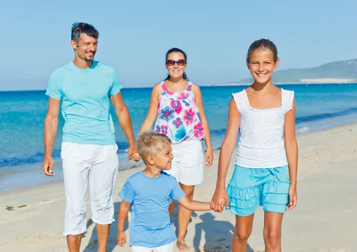 Family of five holding hands walking on sunny beach together
