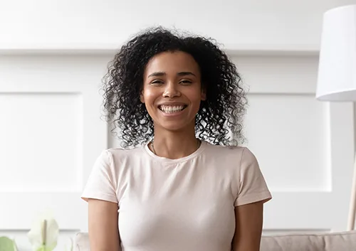 Cheerful african woman sit on couch look at camera