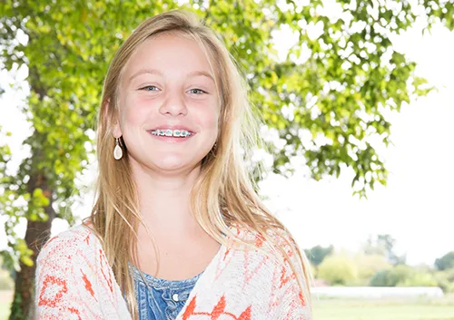 face of a beautiful teenager blonde girl with dental braces on a