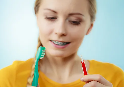 Girl with teeth braces using interdental and traditional brush