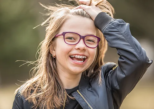 Portrait of a happy smiling teenage girl with dental braces and glasses.