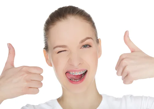 Happy young woman giving double thumbs up with bright smile against white background