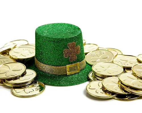 Green leprechaun hat surrounded by gold coins on white background.