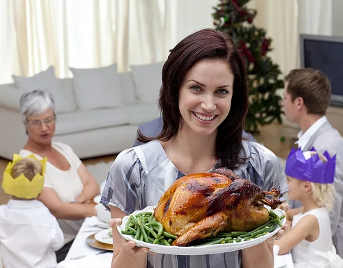 Woman holds roasted turkey at family holiday dinner gathering in living room