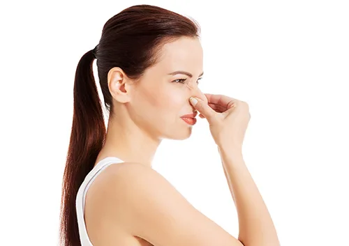 Woman with ponytail touching her nose in profile against white background.