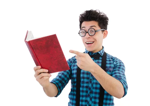 Young man wearing glasses and plaid shirt holding and pointing at red book against white background.