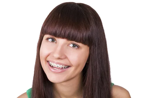 Smiling young woman with straight dark hair and braces, professional headshot against white background.