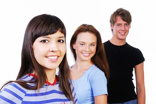 Three smiling teenagers posing together against white background for orthodontics practice