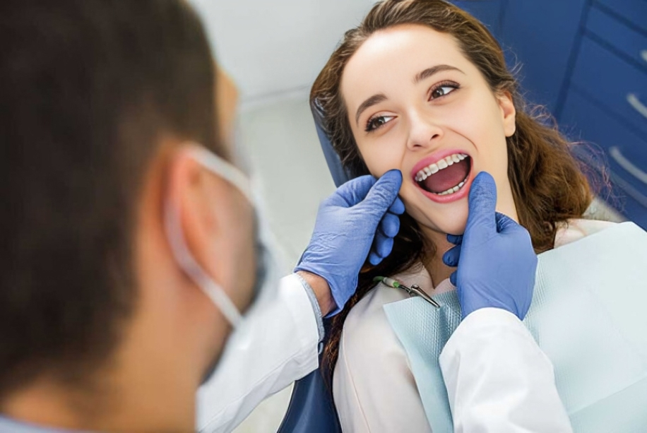 Orthodontist in blue gloves examining patient's teeth during dental checkup at clinic.