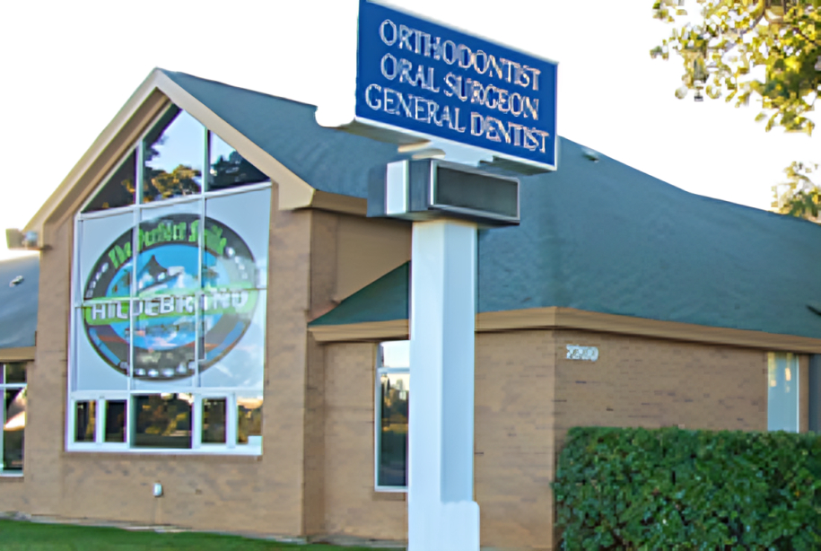 Hildebrand Orthodontics brick building exterior with blue signage and large circular window logo.