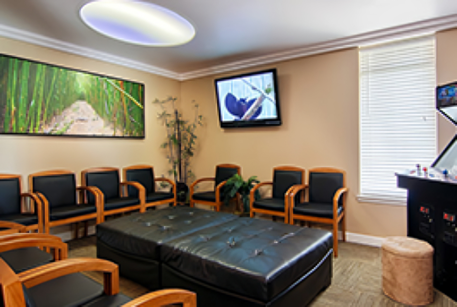Modern orthodontic waiting room with orange and black chairs, artwork, and contemporary furnishings.