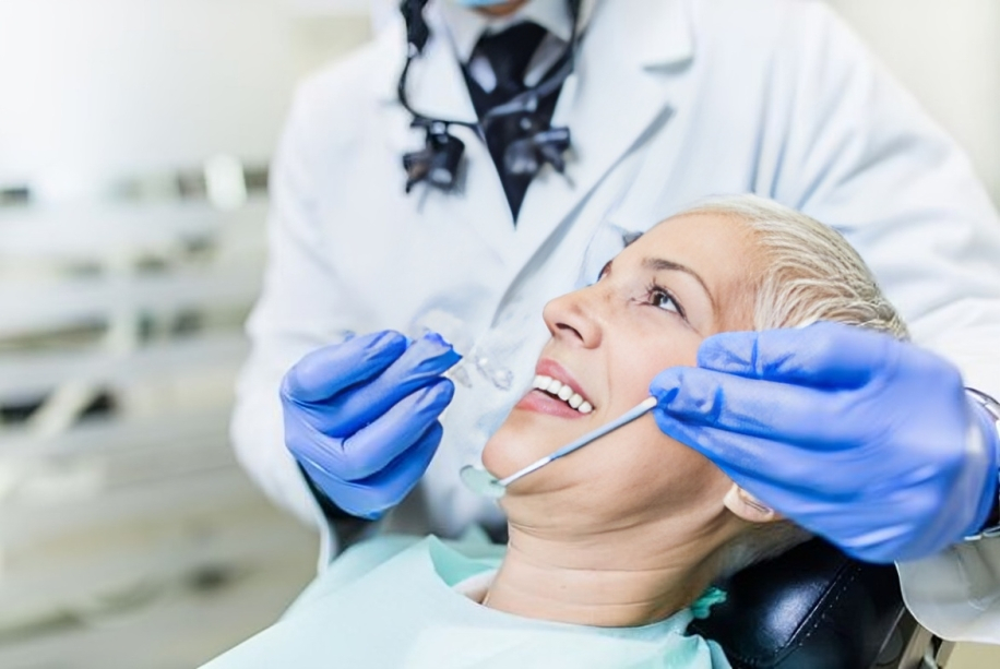 Orthodontist examining patient's teeth during dental checkup in clinical office setting.