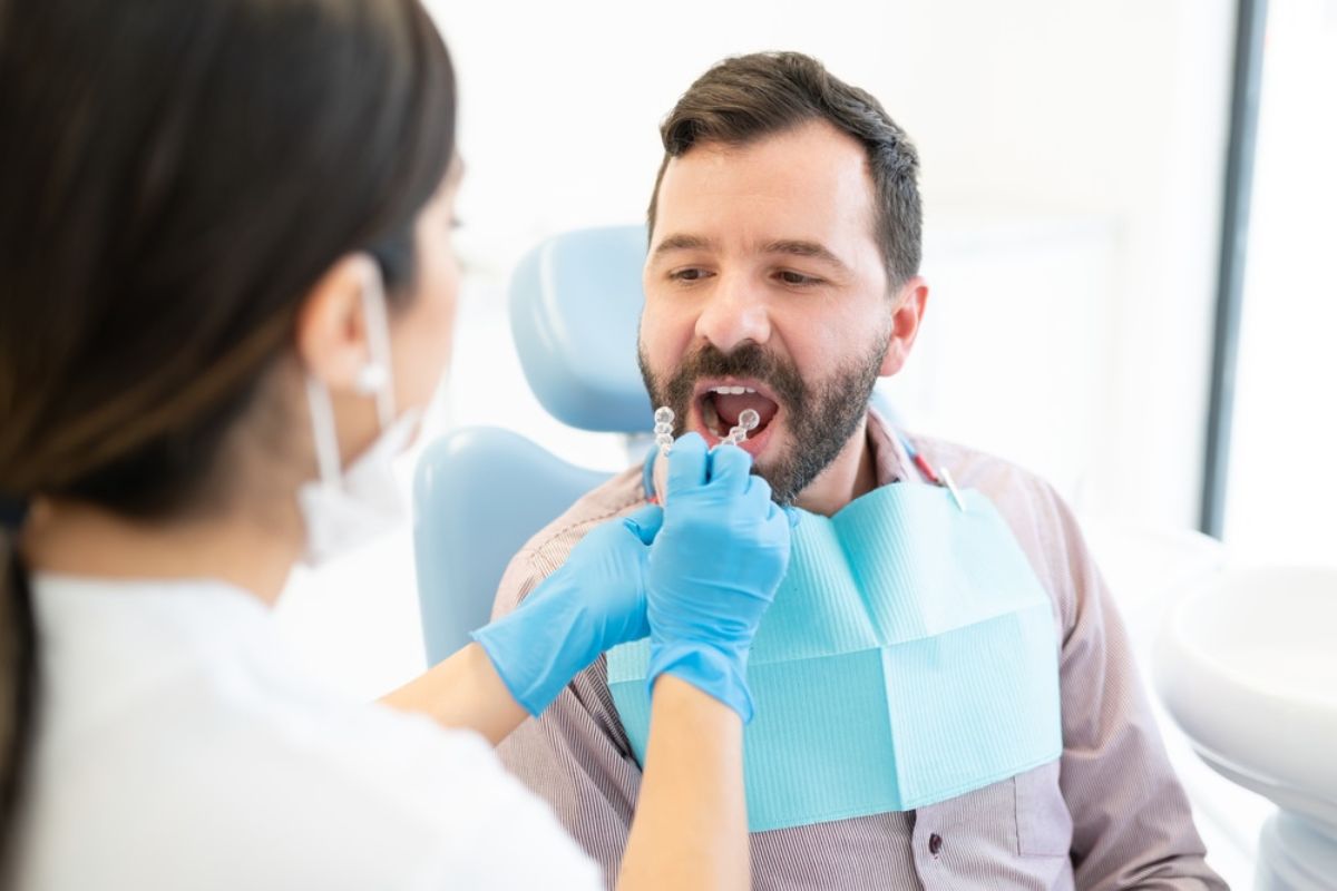 Dentist examines patient's teeth during oral checkup in clinical dental office setting.